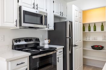 A kitchen with white cabinets and black appliances and a black refrigerator